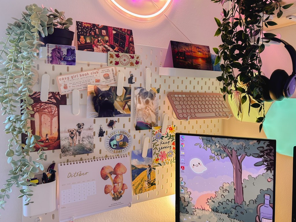 A white IKEA peg board hangs above the gaming desk. It has photos, stickers and a calendar hanging from it. 